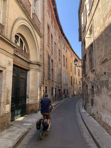 man on a bicycle roading a curve on a narrow street